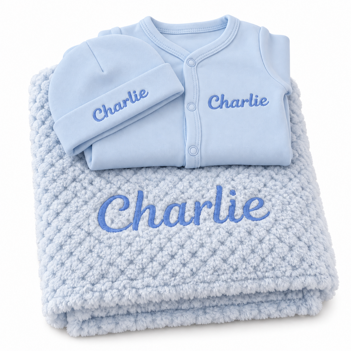 Blue set with blue embroidery showing personalised blanket, sleepsuit and hat on a white background.