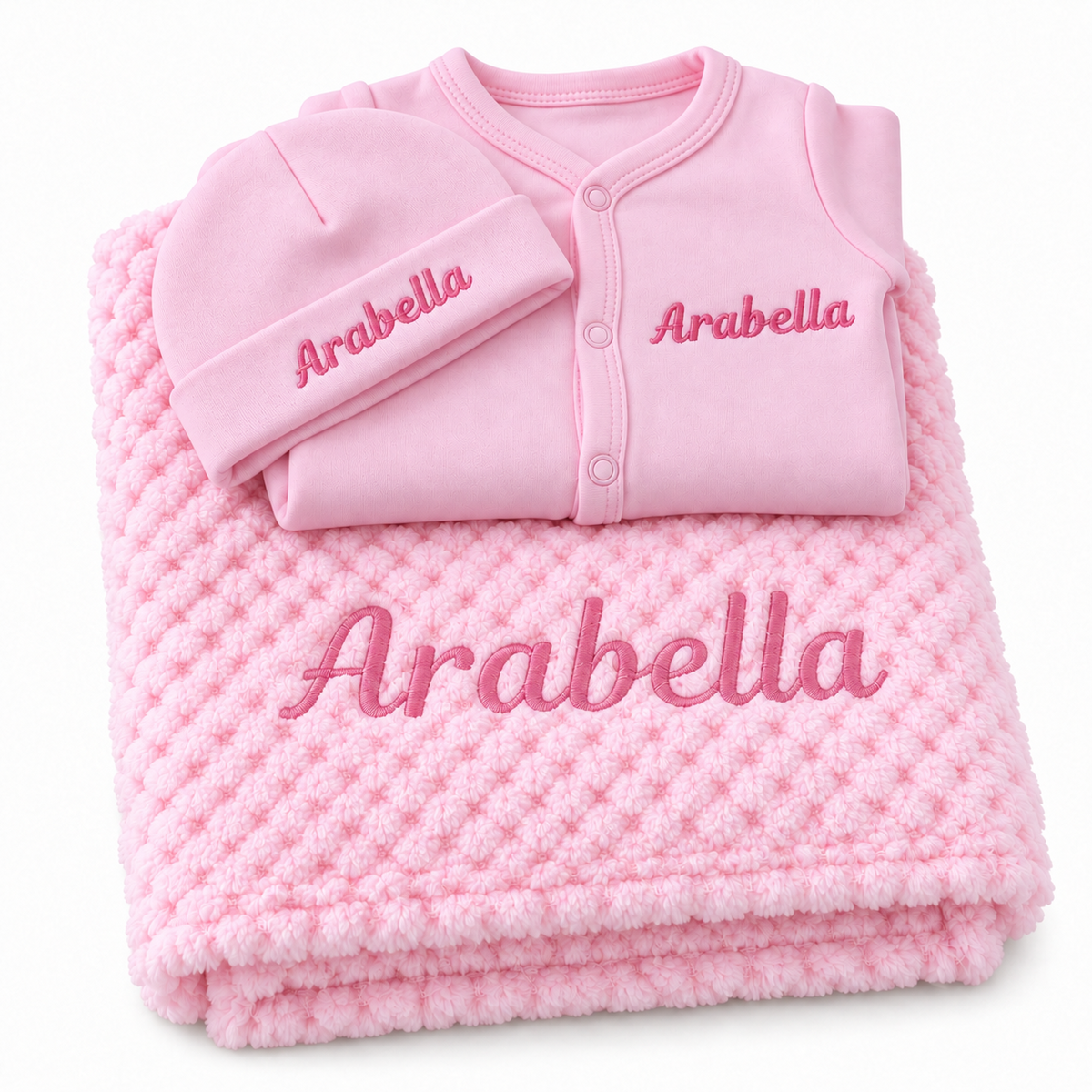 Pink set with pink embroidery showing personalised blanket, sleepsuit and hat on a white background.