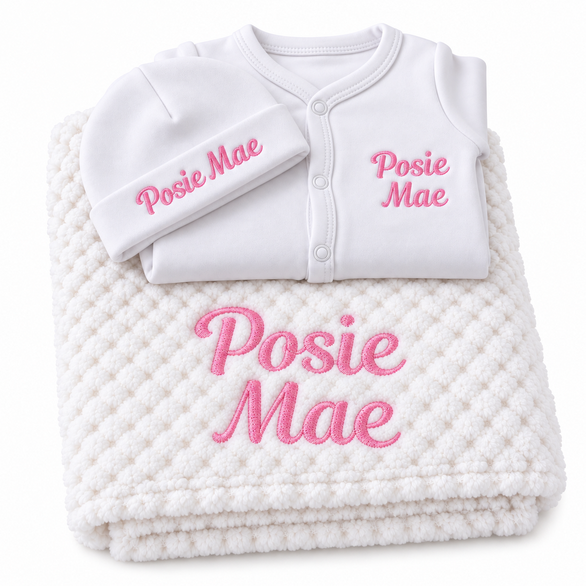 White set with pink embroidery showing personalised blanket, sleepsuit and hat on a white background.